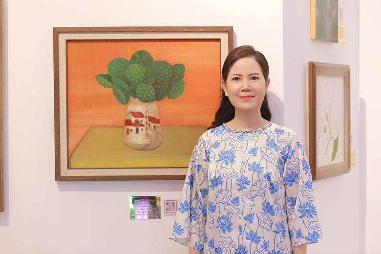 Họa sĩ Kim Đức chụp với các bức tranh sen của mình trưng bày trong triển lãm. Ảnh: BTC