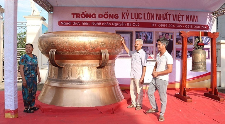 Nghệ nhân Nguyễn Bá Quý (ngoài cùng bên phải) và phiên bản trống đồng Ngọc Lũ lớn nhất Việt Nam. Ảnh: Báo Thanh Hóa